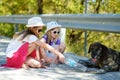 Thirsty black stray dog drinking water from the plastic bottle on hot summer day. Two kids giving cool water to thirsty dog Royalty Free Stock Photo