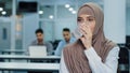 Thirsty businesswoman in hijab drinking pure mineral water in office, thoughtful dehydrated woman employee millennial Royalty Free Stock Photo