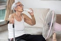 Thirsty elderly woman drinking water to quench thirst,refresh in hot summer weather,senior grandmother enjoying cooling wind from Royalty Free Stock Photo