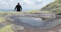 A thirsty and fit tourist runs up and drinks from a small puddle in harsh mountain