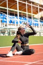 Thirsty fit woman drinking water from plastic bottle, resting after jogging on a treadmill rubber stadium on sunny summer day Royalty Free Stock Photo