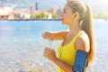 Thirsty fitness woman opens bottle of water after training outdoor. Fit woman using smartphone fitness app on armband for Royalty Free Stock Photo