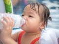Thirsty kid girl refreshing herself and drinking water form plastic bottle in the pool Royalty Free Stock Photo