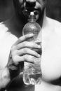 Thirsty man with beard and naked chest holds water bottle