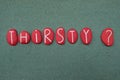 Thirsty ? Question word composed with red colored stone letters over green sand