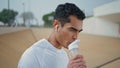 Thirsty runner drinking water closeup. Handsome athlete resting after workout