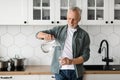 Thirsty Senior Man Pouring Water From Jug To Glass In Kitchen Interior Royalty Free Stock Photo