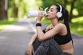 Thirsty After Training. Young asian girl drinking water, resting after jogging outsoors Royalty Free Stock Photo