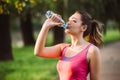 Thirsty woman drinking water to recuperate after jogging