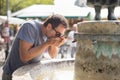 Thirsty young casual cucasian man drinking water from public city fountain on a hot summer day Royalty Free Stock Photo