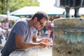 Thirsty young casual cucasian man drinking water from public city fountain on a hot summer day Royalty Free Stock Photo