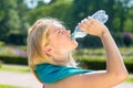 Thirsty young woman finishing water from bottle.