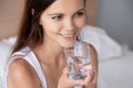 Thirsty young woman holding glass drinking water in bed Royalty Free Stock Photo