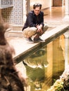 Thirty-year-old man looks smiling at himself in the reflection of a fountain