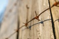 Thorn rusty wire along a wooden fence, old boards and rusty wire with spikes Royalty Free Stock Photo