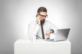 Thoughful bearded young worker in white shirt and black tie are sitting in office on desk and talking with partner on phone also