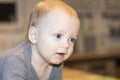 Thoughful big-eyed toddler looking away on blurred background. Close-up