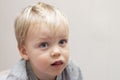 Thoughful big-eyed toddler looking away on grey background. Close-up. Copy space