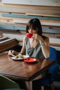 Thoughful woman drinking coffee with a pie. Sitting behind a table in a cafe. Royalty Free Stock Photo