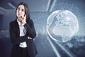 Thoughful young european businesswoman standing in blurry office interior with glowing globe hologram. Global business and