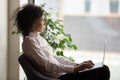 Thoughtful African American businesswoman looking out window, using laptop