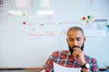 Thoughtful african american man reading sitting over whiteboard Royalty Free Stock Photo