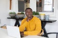 Thoughtful african american man using laptop at home and looking away Royalty Free Stock Photo