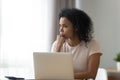 Thoughtful African American woman using laptop, pondering task Royalty Free Stock Photo