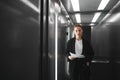 Thoughtful ambitious businesswoman is standing in the elevator and trying to remember somenthing. Puzzled female employee is