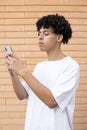 A thoughtful American man holding a phone and writing a post under a photo on a social networking site Royalty Free Stock Photo