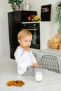 Thoughtful, angry boy eats breakfast cookies and milk and looks at the camera Royalty Free Stock Photo