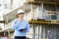 Thoughtful architect with clipboard and pen standing at site Royalty Free Stock Photo