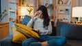 Thoughtful Asia lady holding phone feeling sad waiting for call sit at sofa in living room at house night feel lonely, Sad Royalty Free Stock Photo