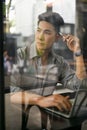 Thoughtful Asian businessman sits in a coffee shop, looking out the window Royalty Free Stock Photo