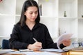Thoughtful asian businesswoman checking financial reports at her office desk Royalty Free Stock Photo