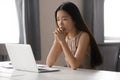 Thoughtful Asian businesswoman looking at laptop screen, pondering task