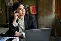 Thoughtful Asian businesswoman looking out the window with a pensive, thinking face Royalty Free Stock Photo