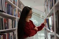 Thoughtful asian student girl in glasses choosing book in college library or bookstore Royalty Free Stock Photo