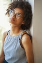 Thoughtful attractive woman in circle spectacles seated by the window