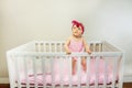 Thoughtful baby girl stand in the crib bed smiling Royalty Free Stock Photo