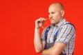 Thoughtful bald man in a uniform looks away biting his safety glasses Royalty Free Stock Photo