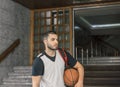 Thoughtful basketball player, leaves the portal of a building, concentrated on his next game