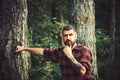 Thoughtful bearded man in lumberjack shirt with tattoo on his arm wandering in forest. Lone hiker exploring wonders of Royalty Free Stock Photo