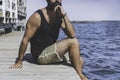 Thoughtful bearded man sitting on wooden pier on seaside and looking into the distance on the horizon in the sea. human