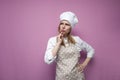 Thoughtful beautiful girl cook in kitchen clothes thinks over an idea on a pink background, a woman housewife dreams and looks at