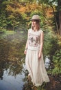 Thoughtful beautiful woman in long dress near river in forest Royalty Free Stock Photo