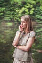 Thoughtful beautiful woman near river in forest Royalty Free Stock Photo