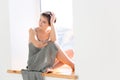 Thoughtful beautiful young woman sitting on window sill and dreaming Royalty Free Stock Photo