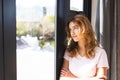 Thoughtful biracial woman looking out of window at home on sunny day, copy space
