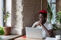 Thoughtful Black man watching educational webinar on laptop, studying, remotely online work in cafe. Royalty Free Stock Photo